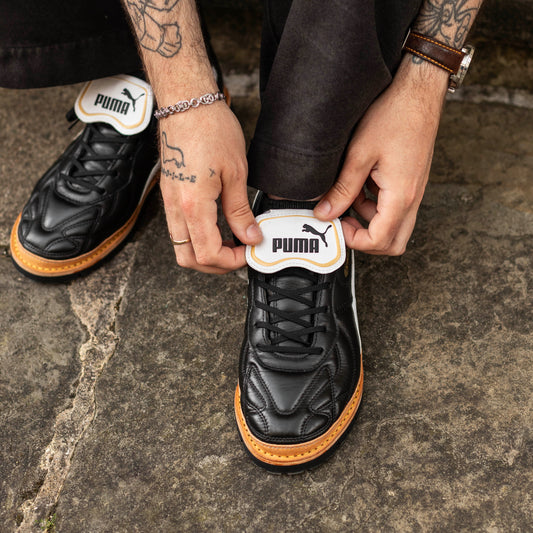 Person wearing black Puma shoes on a stone surface